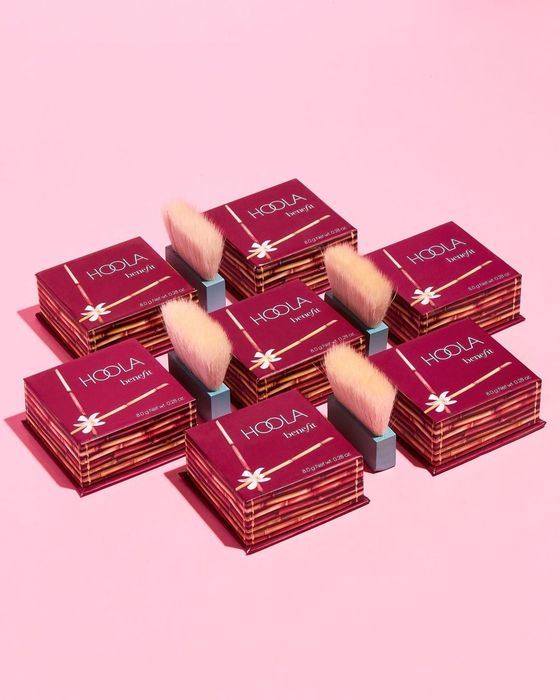 A collection of Hoola bronzer packages with fluffy brushes nestled in between.