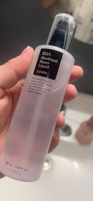 A reviewer holding a bottle of power liquid.