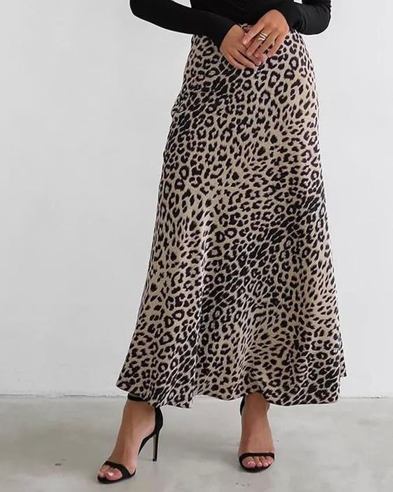 A model shows off a leopard print ankle-length skirt paired with black high-heeled sandals. Their top and face are not visible.
