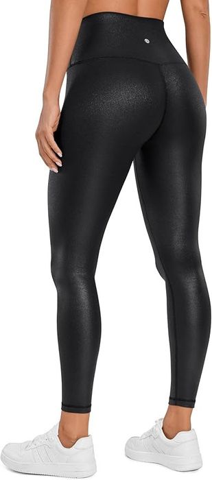 A person is shown from behind, wearing black, high-waisted, figure-hugging leggings and white sneakers