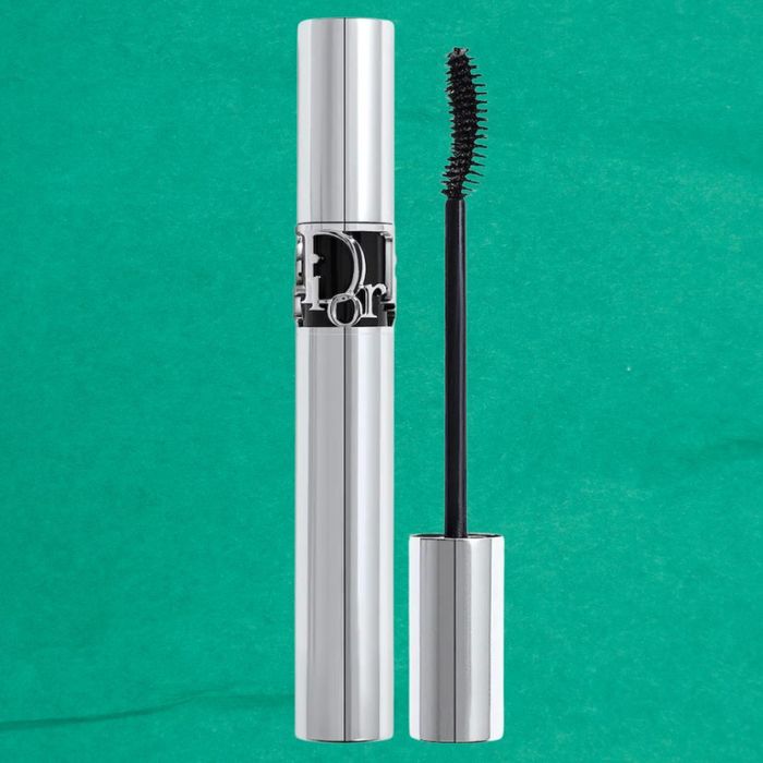 A silver Dior mascara tube with the wand applicator removed and placed next to it, set against a simple background.