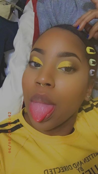 A reviewer showcasing bright yellow eyeshadow to illustrate how the primer helps intensify the color.