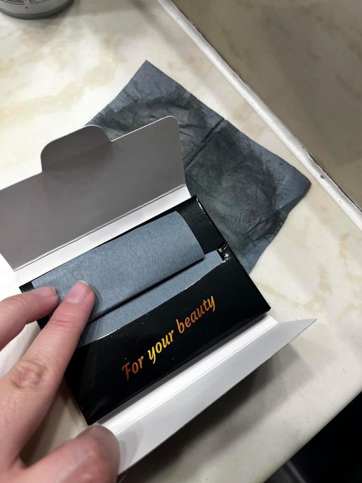 An open pack of oil-absorbing sheets, with text displayed.
