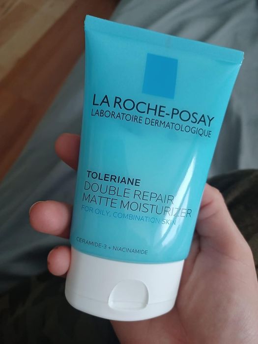 A reviewer holding a tube of La Roche-Posay Toleriane Double Repair Matte Moisturizer for oily, combination skin.