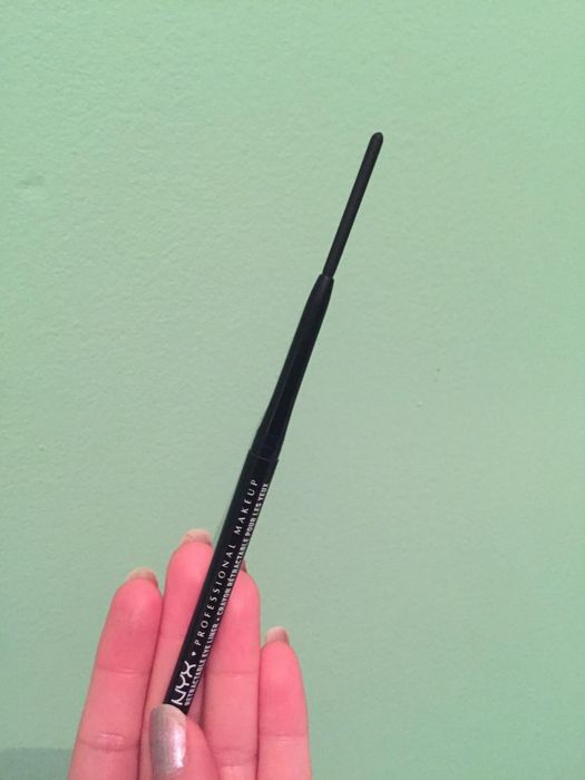 A reviewer holding up the eyeliner pencil.