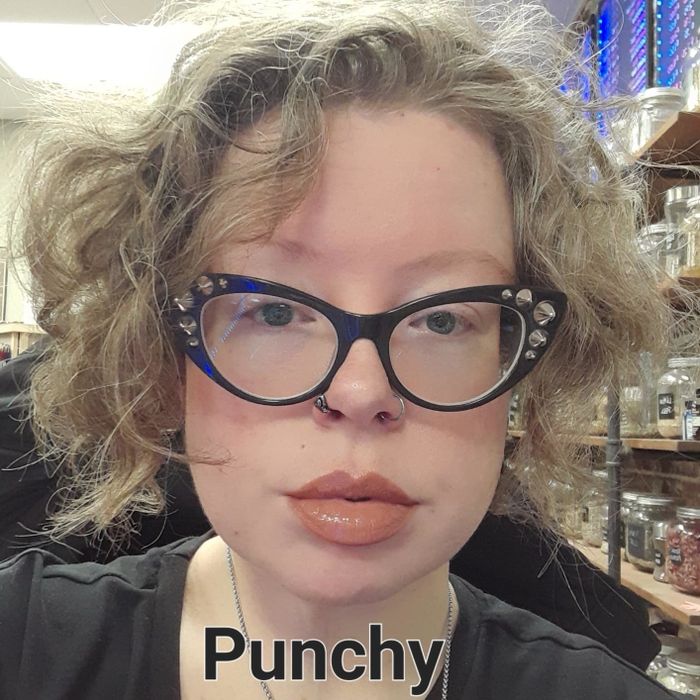 A person with curly hair, black glasses, and a nose ring, tagged as