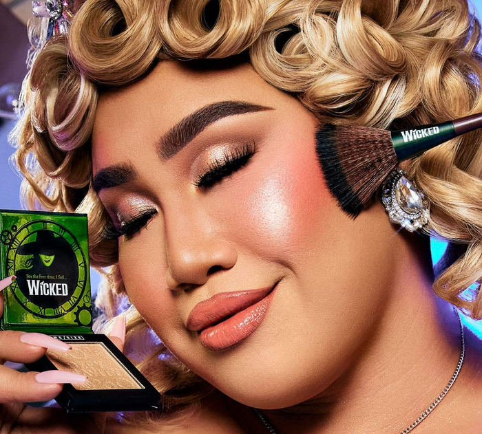 A person applying makeup with a brush labeled