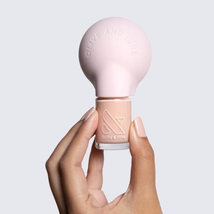 A model demonstrating the poppy grip tool on top of a nail polish bottle.
