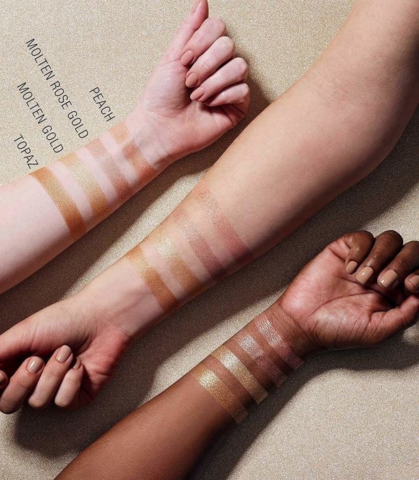 Three arms of different skin tones showing swatches of the Maybelline Master Chrome Metallic Highlighter powder