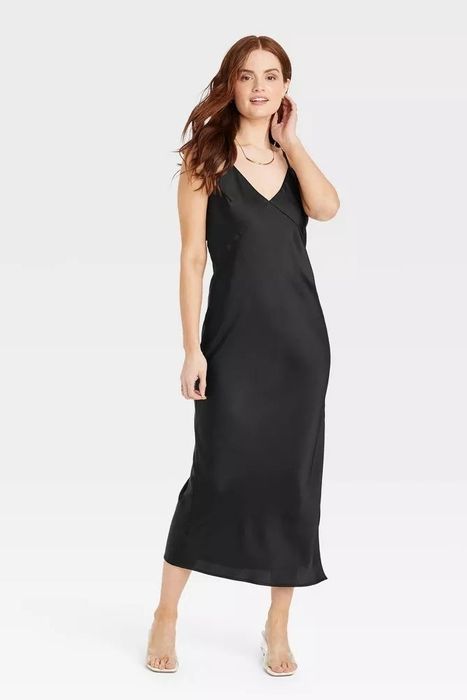 A person poses in a sleek, sleeveless, ankle-length dress, showing off a style perfect for formal or elegant events.
