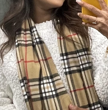 Person rocking a plaid scarf and cozy sweater, snapping a selfie to flaunt their winter style
