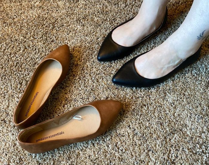 A reviewer showcasing black and brown flats