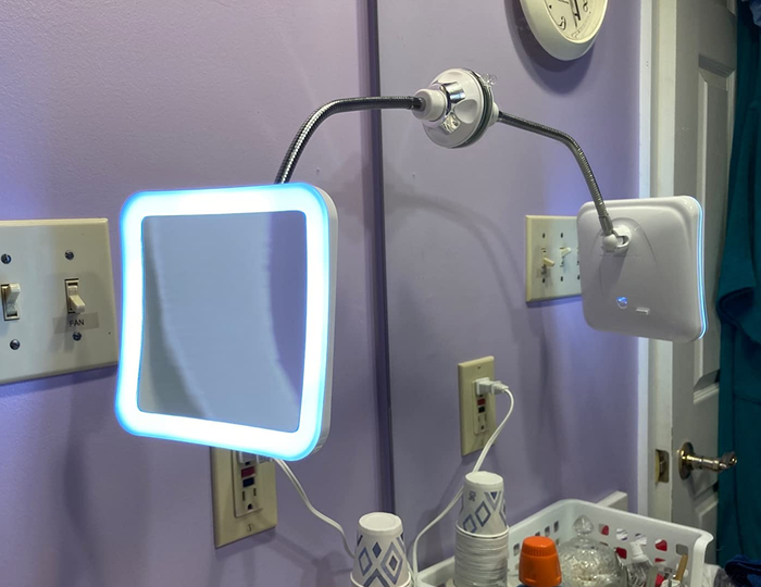 A reviewer's photo showing the gooseneck mirror mounted on a larger bathroom mirror