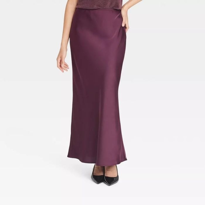 A person showcasing a long, sleek satin slip skirt paired with black heels.