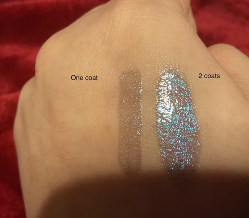 A reviewer's hand showing lip gloss swatches, illustrating how the product looks with one and two coats.