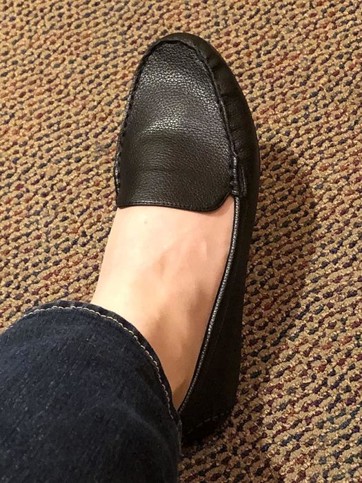 A reviewer showcasing a sleek pair of black shoes.