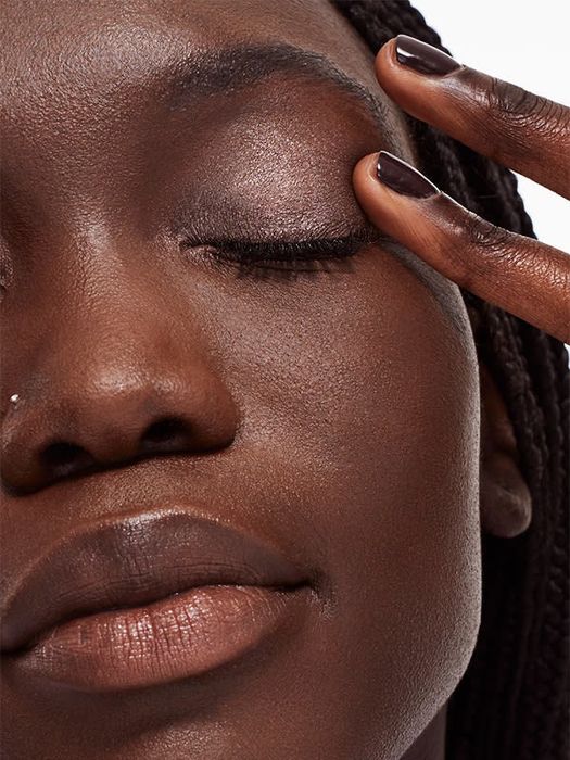 A model gently patting one of the liquid shadows onto their eyelid.