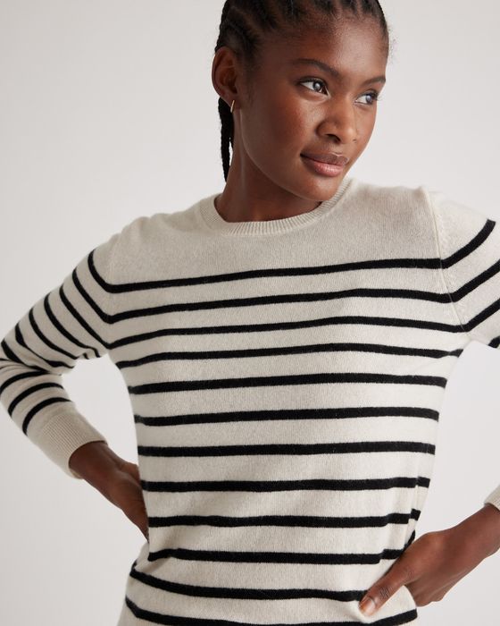 A person sporting a striped sweater, glancing to the side with hands on hips, featured in a shopping article