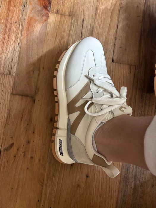 Person wearing white sneakers with a chunky sole and laces, shot from above
