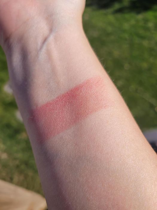 A reviewer showcasing the peony-colored shimmer shade of the multi-stick