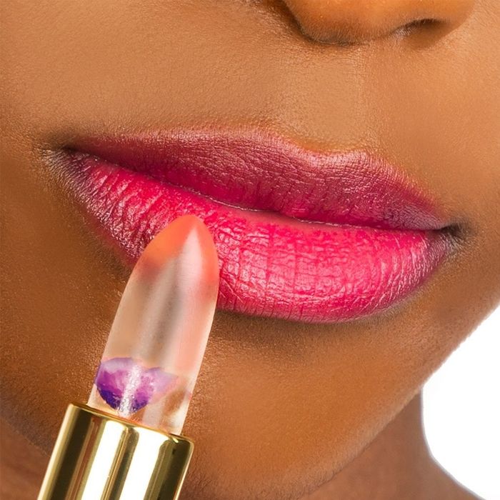 A model applying the clear lip balm, which contains a tiny flower inside.