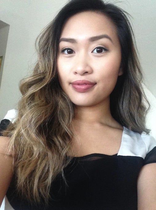 A reviewer with wavy hair, wearing the Lolita shade, smiles softly at the camera.