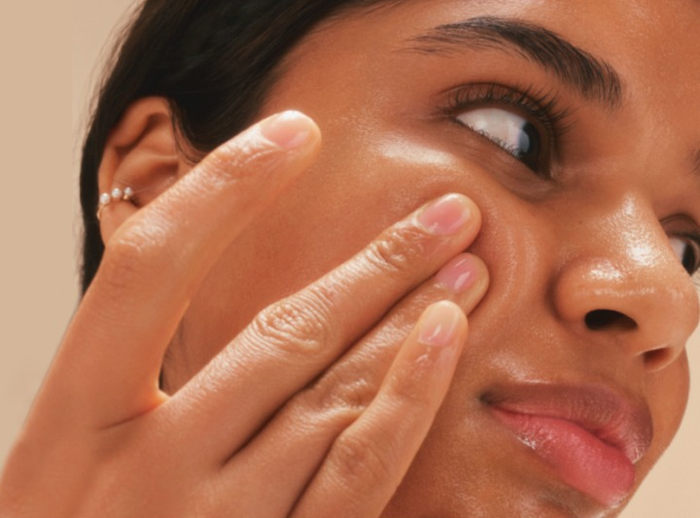 A model gently massaging the cleansing oil onto their cheek.