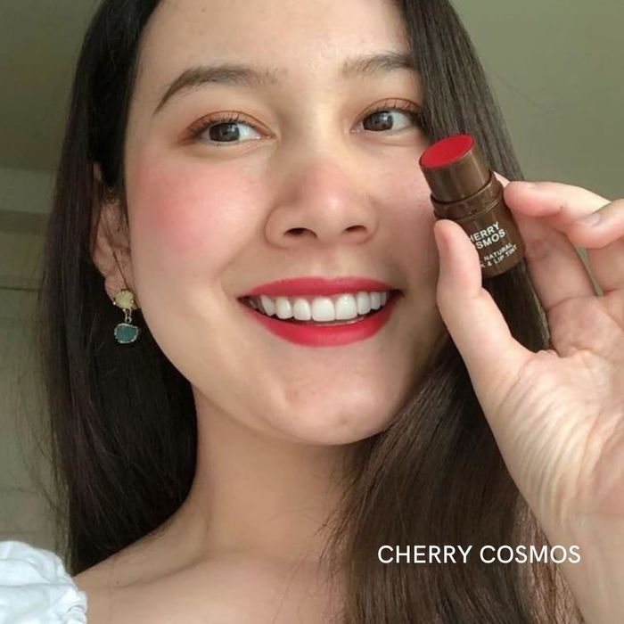 A model showcasing the cherry cosmos shade on both their cheeks and lips.
