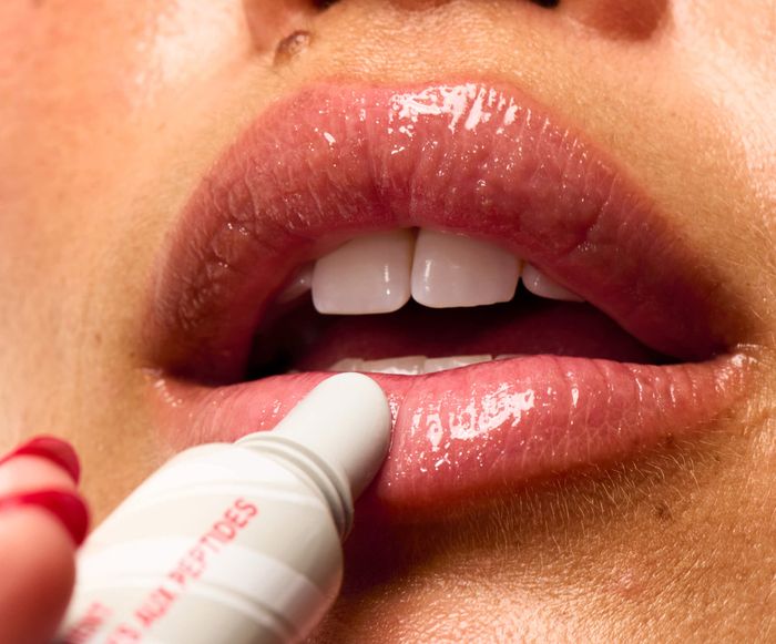 A close-up of lips applying a tube of lip gloss, demonstrating a beauty product for a shopping article