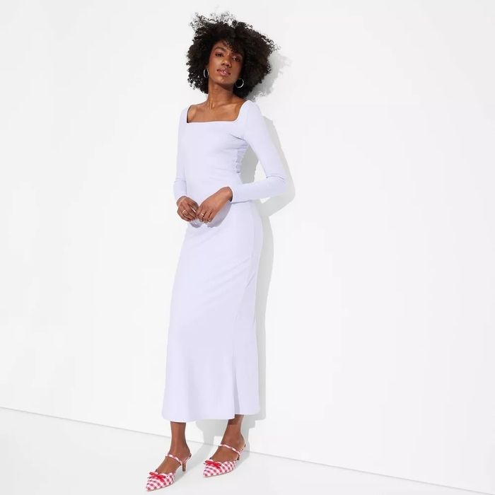 Woman strikes a pose in a long, form-fitting dress with a square neckline, paired with stylish gingham shoes. Perfect for a chic shopping outing.