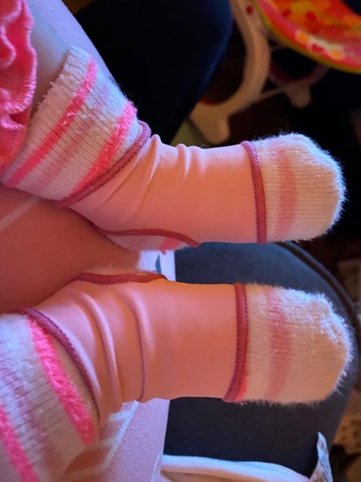 A reviewer photo showing a pink sleeve over a baby's socks
