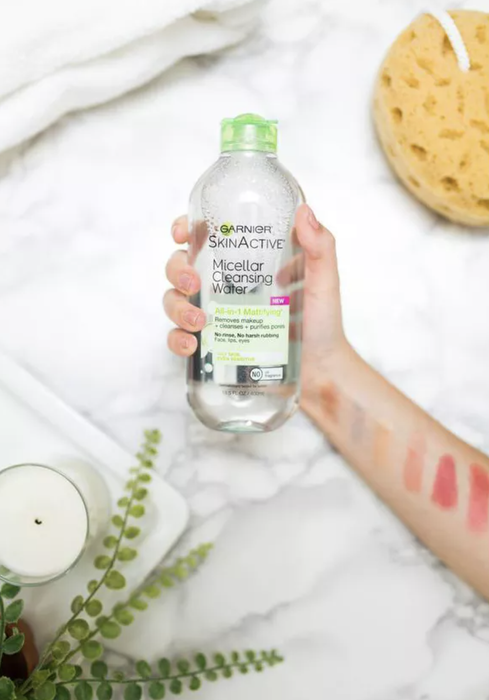 A model holding a bottle of micellar cleansing water
