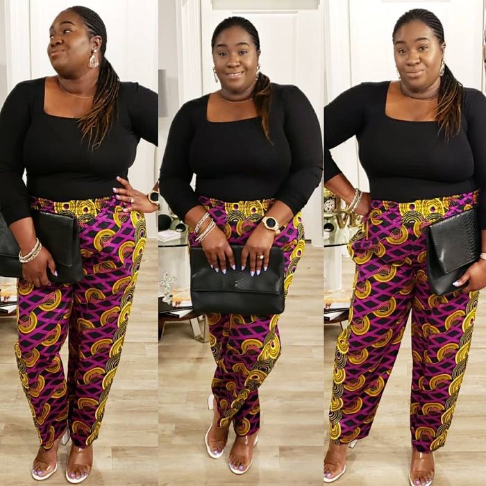 Reviewer in a black top, patterned pants, holding a clutch, with sandals
