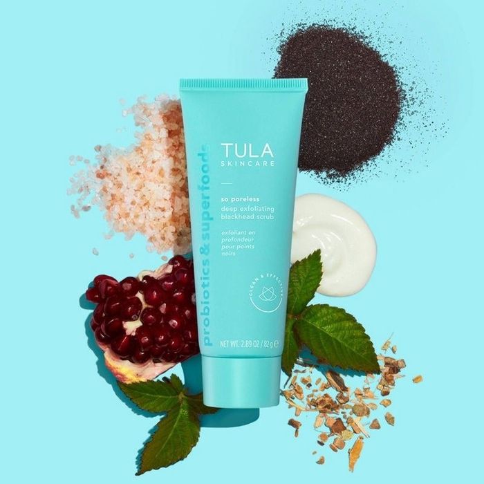 A tube of face scrub containing seeds, leaves, and berries