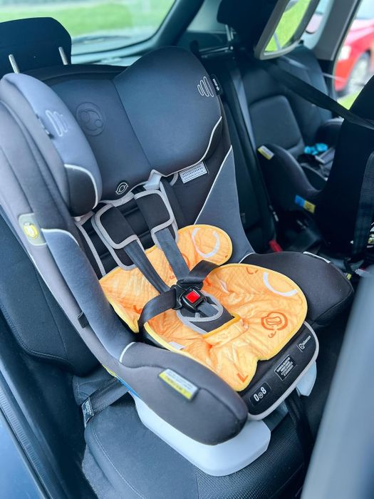 A child's car seat is safely secured in the back seat of a vehicle, shown from the side.