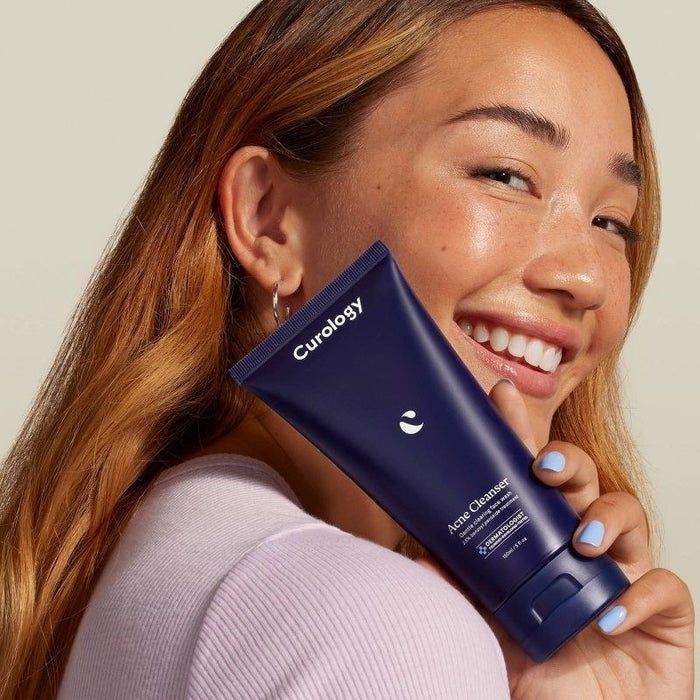 A person holding a tube of facial cleanser
