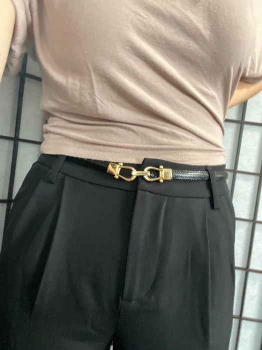 Person pairing black pleated pants with a gold buckle belt, ideal for a shopping guide article.