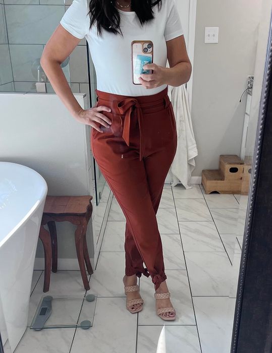 Person showcasing copper-colored paper bag pants with bows at the waist.