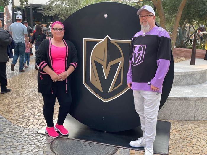 A reviewer in a black and pink outfit paired with pink shoes, alongside another person wearing a purple and black top with white pants.