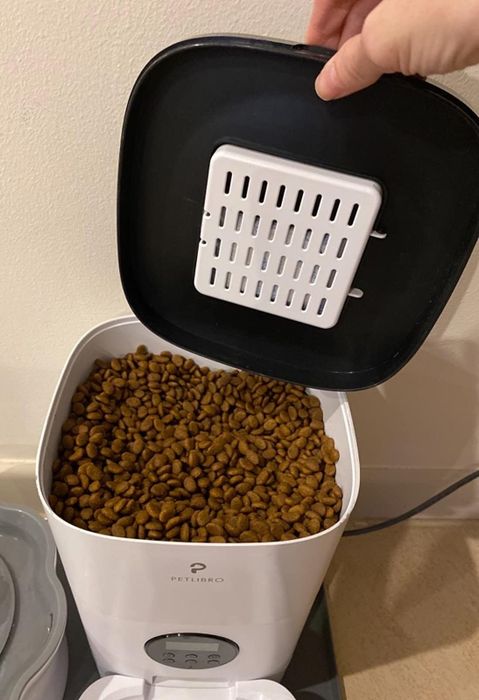 A close-up view of the top of the automatic cat feeder, with a pile of dry kibble ready to be dispensed