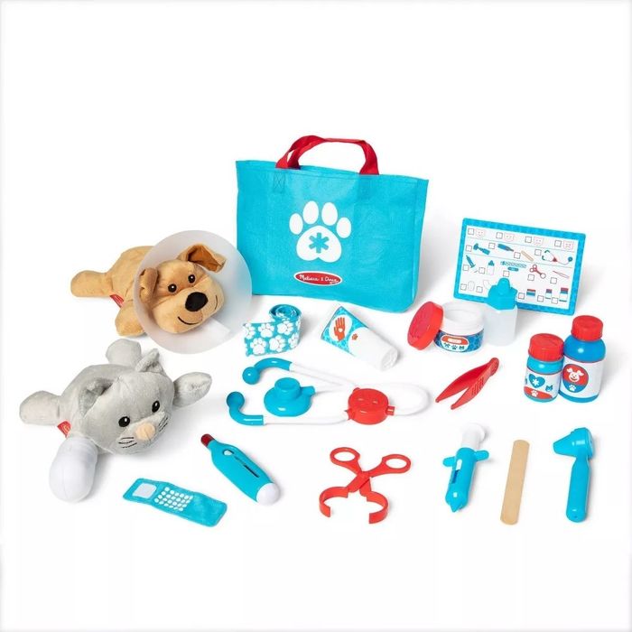 An assortment of toy veterinary tools, including a stuffed dog and cat, play medical instruments, and a blue tote bag featuring a paw print logo, ready for young vets to get to work.
