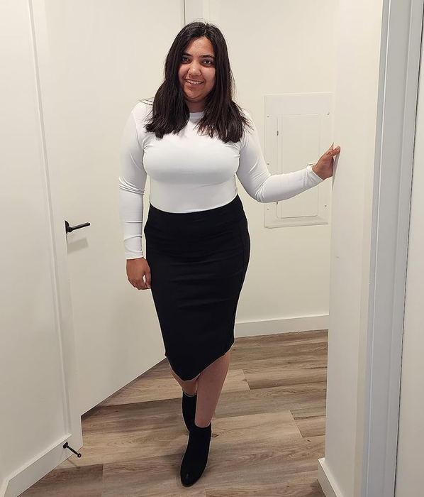 Reviewer dressed in a white top, black pencil skirt, and ankle boots.