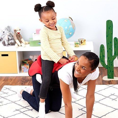 A happy child rides on the back of an adult woman, who is on all fours in a room filled with toys and a globe. They are both enjoying a fun moment together.