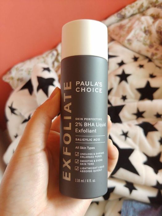 A reviewer holding the bottle of liquid exfoliant.