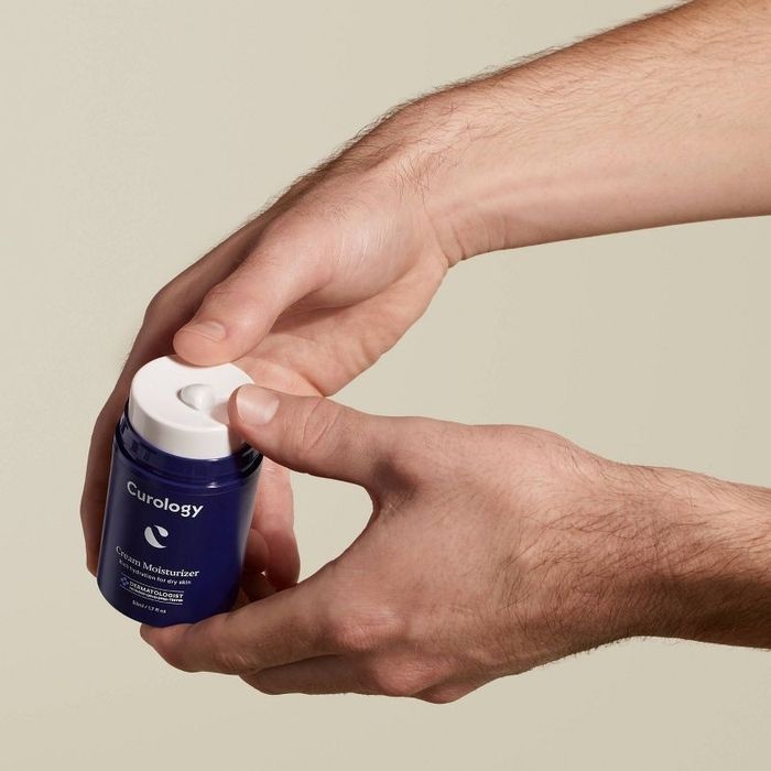 A person dispensing face cream onto their hand