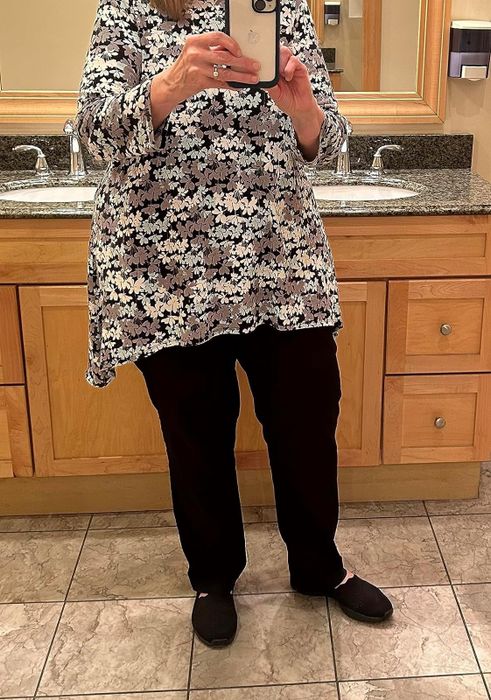Person in a floral top paired with black trousers.