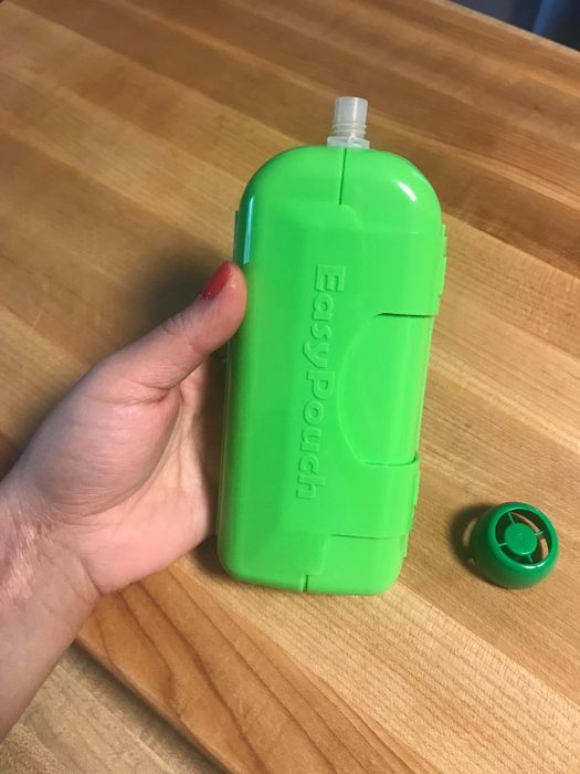 A hand grasps a green container.