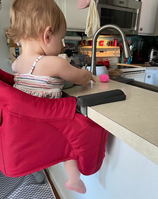 Side view of a reviewer's child sitting in a red high chair at a kitchen bar