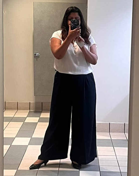 Reviewer in wide-leg trousers and a white blouse.