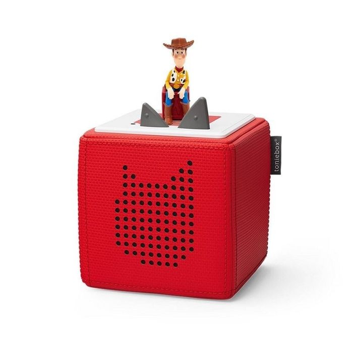 A Woody character figure from Toy Story placed on a red Toniebox audio player with a cat design in black dots.